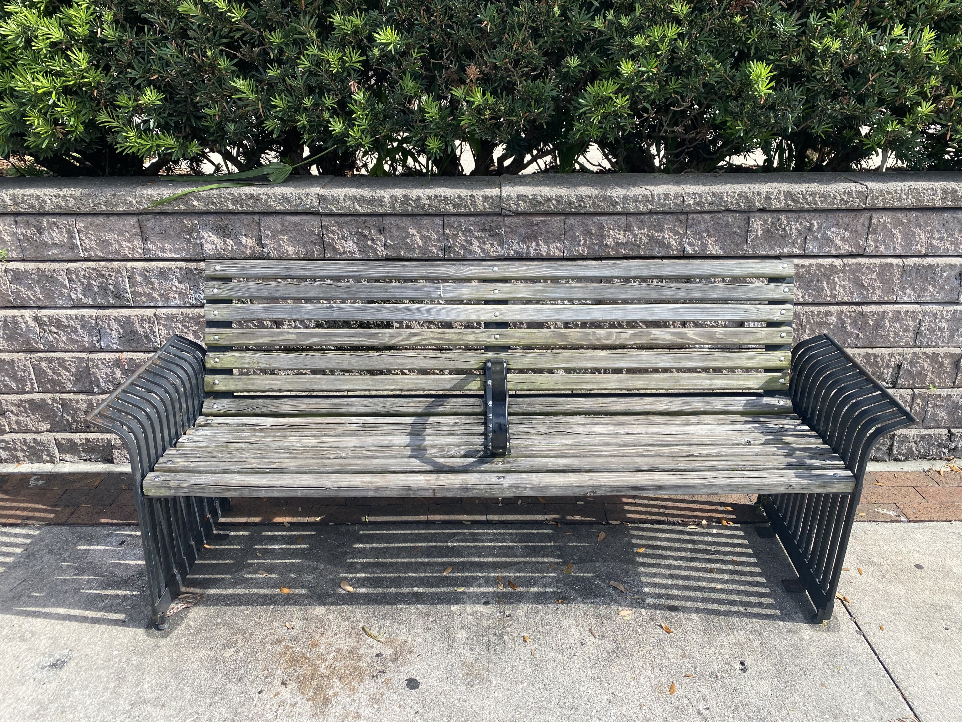 An park bench with a metal separator in the middle.